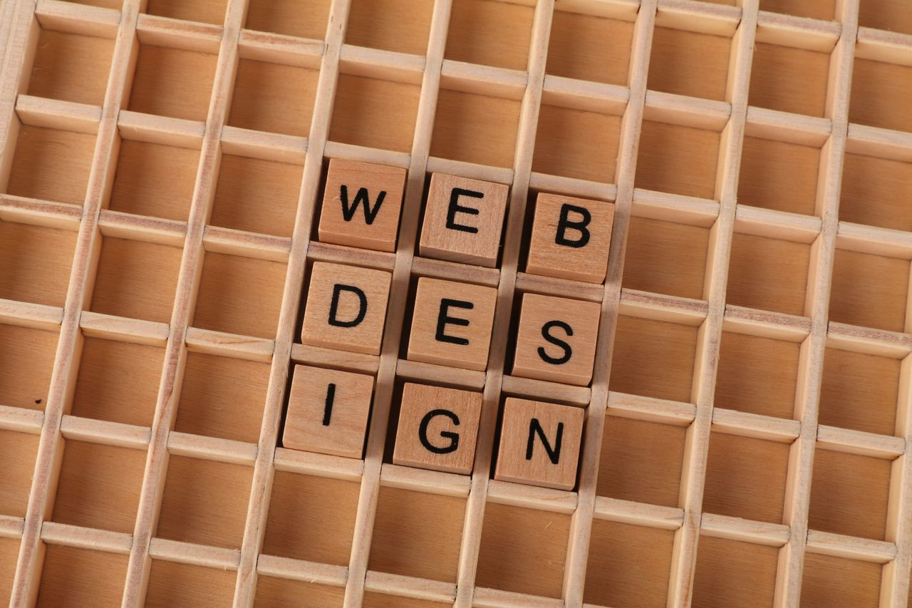 our-services-1 Wooden blocks spelling web design on a grid background symbolizing creative digital design concepts.